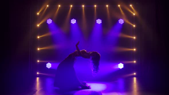 Silhouettes of a Woman in Exotic Costume Performs a Belly Dance Moves Semi Nude Body. Shot in a Dark