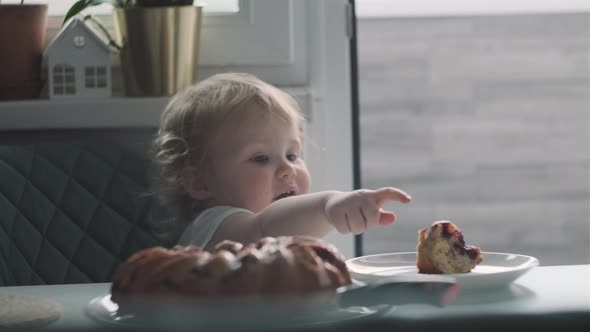 Funny Baby Girl Child in White Tshirt Sit in Green Chair in Kitchen and Eat Pie