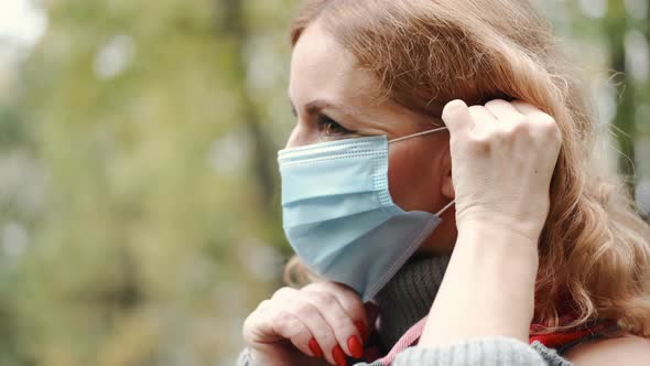 Woman Put on Protective Mask in a Park