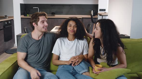 Group of Three Friends One Man and Two Women Talking Laughing Together While Sitting on the Couch