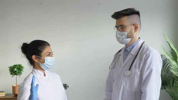 Portrait of Two Doctors A Man and a Woman Give Each other a high five, Dressed in Dressing Gowns