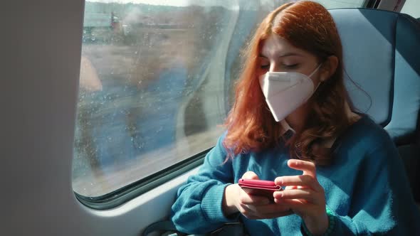 Young Red Hair Girl Travels for Work By Train with Phone and Ffp2 Mask