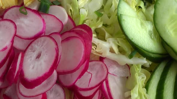 Salad ingredients in a glass bowl, cabbage, radish, onion, cucumber, egg.