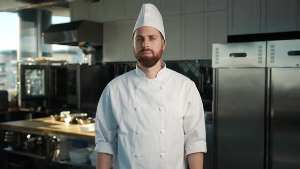 Professional kitchen, portrait: Male Chef folds his arms and looks at the camera