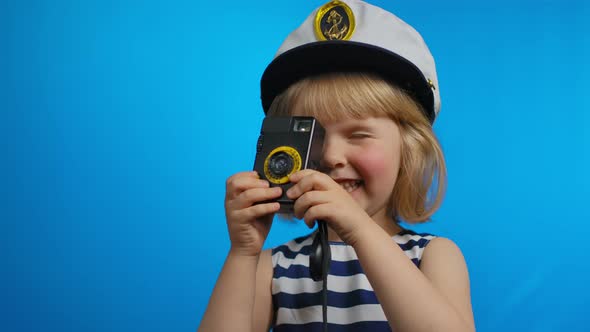 Cute Little Blond Girl is Using Retro Photo Camera for Shooting Pictures