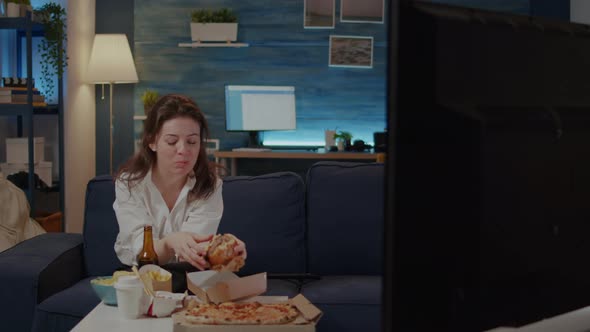 Person Eating Delicious Hamburger and Fries in Living Room