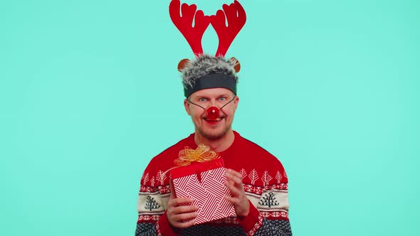 Cheerful Man in Sweater Santa Christmas Hat Getting Present Gift Box Expressing Amazement Happiness