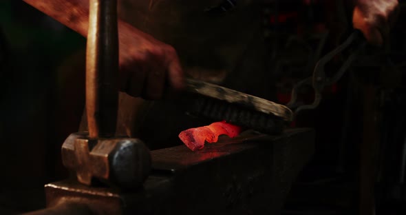 Mid-section of blacksmith using wire brush on hot iron