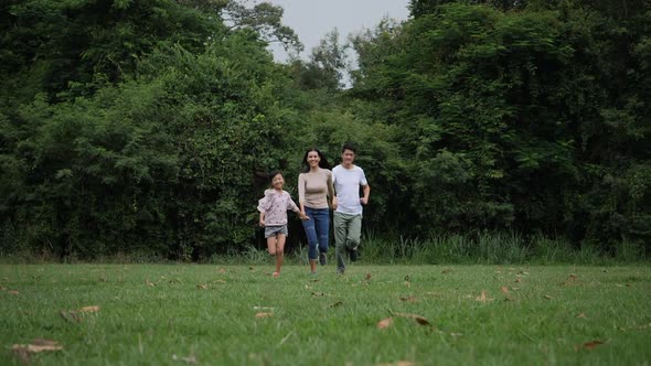 Slow motion of parents with daughter running enjoy in the park