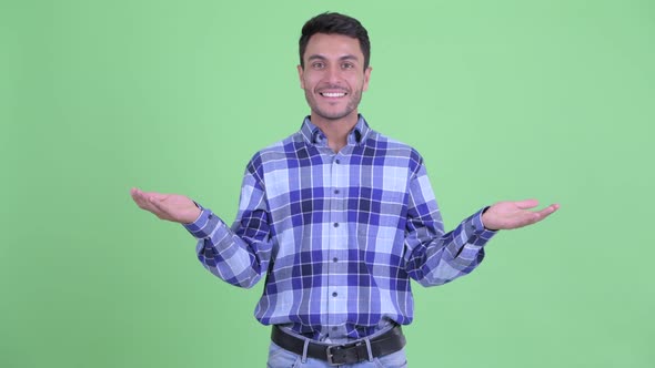 Happy Young Handsome Hispanic Man Comparing Something