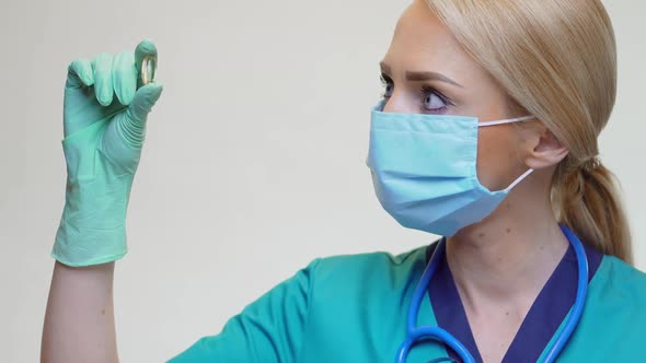 Medical Doctor Nurse Woman Wearing Protective Mask and Rubber or Latex Gloves - Holding Pills