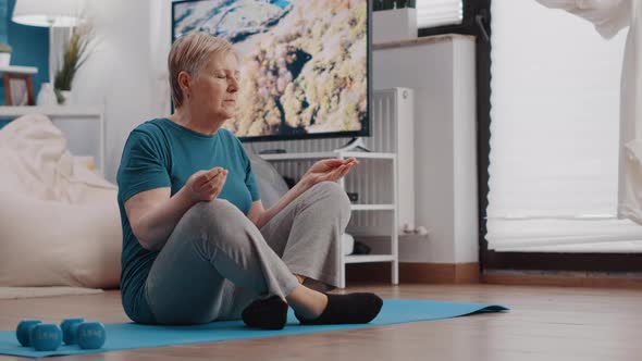 Elder Person Sitting in Lotus Position on Yoga Mat to Meditate