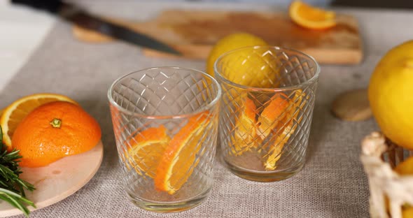 Female hand put orange in glasses, making fresh lemonade