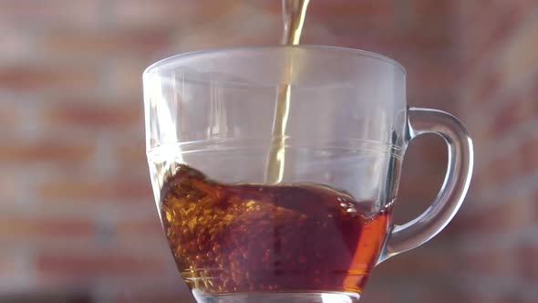 Fresh steamed black tea is poured into a transparent glass outdoors