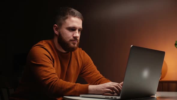 Confident Man Using Laptop Computer at Kitchen Table