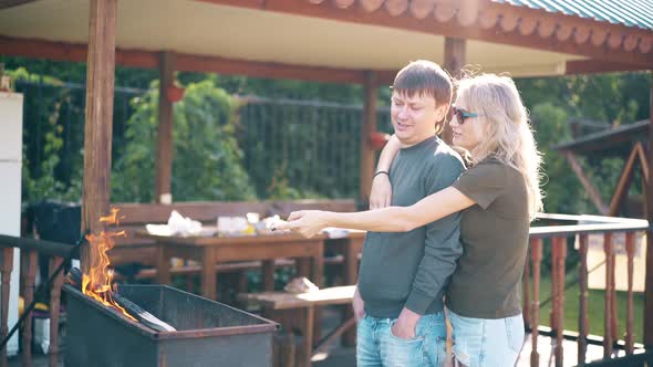 Travelling: Young Guy with Girl, Standing Near the Barbecue