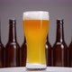 Glass with beer and foam rotates against the background of bottles - VideoHive Item for Sale