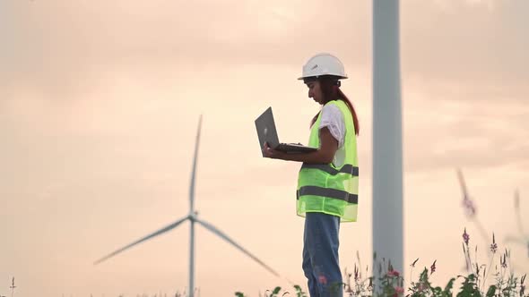 Woman Ecology Specialist Checking with Laptop Correct Operation Windmills Sunset