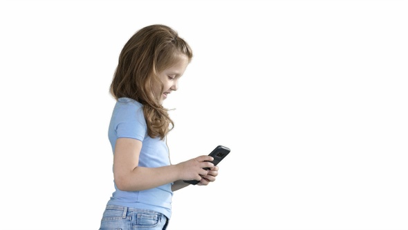 Little girl is playing with smartphone while walking on