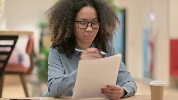 Young African Woman Reading Documents at Work
