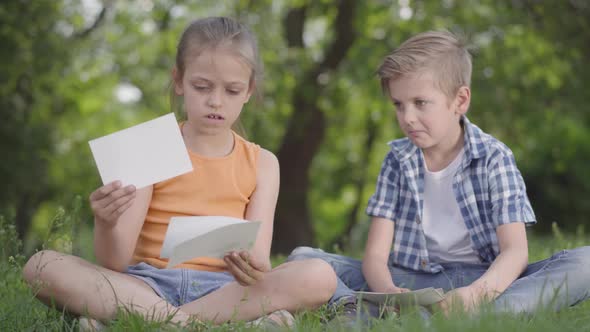 Portrait of Cute Handsome Boy in Checkered Shirt and Girl with Long Hair Looking at Sheets of Paper