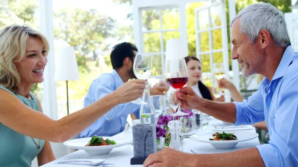 Two friends toasting glasses of wine in restaurant