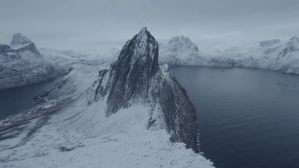 Aerial drone view approaching the snowy Segla mountain, blue hour in Senja, Norway