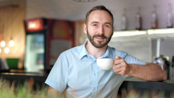 Attractive Happy Male Having Good Time Drinking Coffee or Tea Looking at Camera