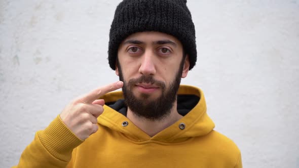 Young Bearded Man Pointing Finger To His Mouth. close up