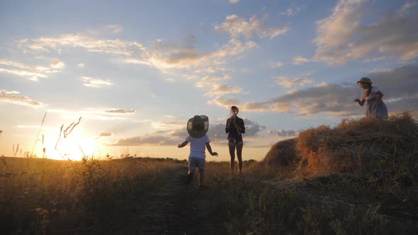 Young Mom and Little Son in the Sunset Catches Soap Bubbles in Meadow. Relax with Child in Nature