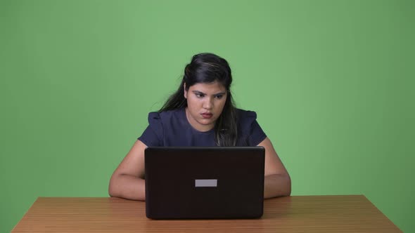 Young Overweight Beautiful Indian Businesswoman Against Green Background