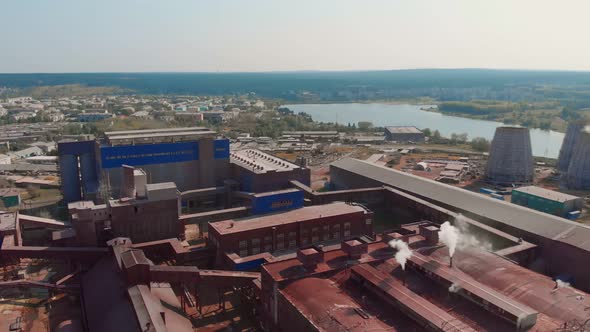 A Drone Flies Over a Factory with Many Pipes That Smoke on the Outskirts of the City Polluting the