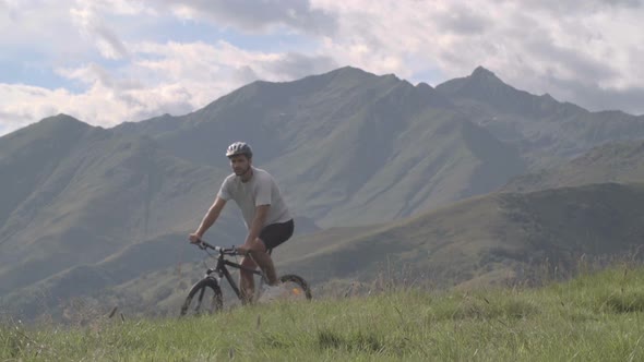 Young Athletic Man in Summer Day is Cycling Outdoor on Mountain with His Mountain Bike Slow Motion