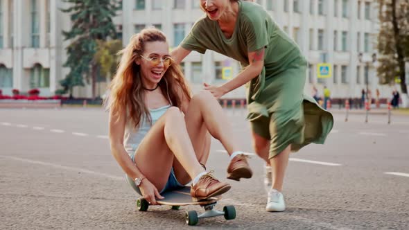 Cool Young Girls Longboards and Skateboards Through Stylish Hip Cultural Part of the City