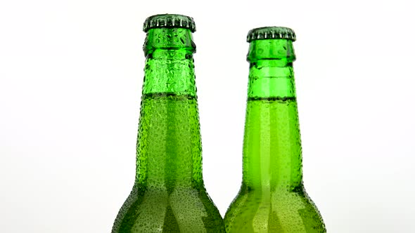 Three green beer bottles rotating over white