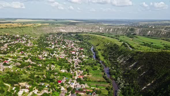 Aerial drone view of nature, valley with river and village, hills and fields, greenery, Moldova