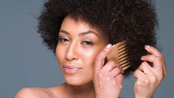 Amused African American Woman Combing Her Hair