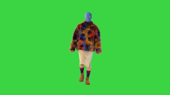 Caucasian Girl in Balaclava and Multicolored Fur Coat Walks on a Green Screen Chroma Key