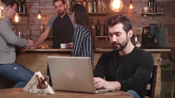 Young Handsome Man Typing a Message on His Laptop While Relaxing in a Vintage Coffee Shop