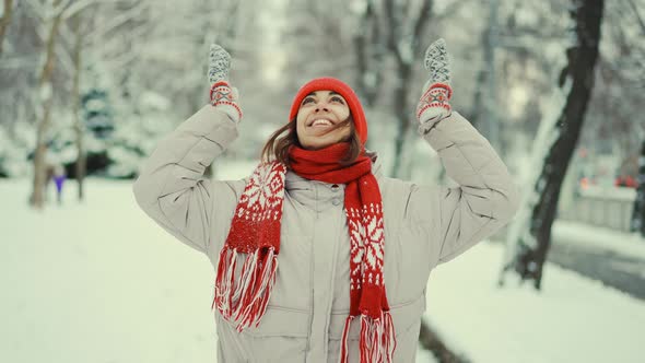 Cheerful Smiling Woman in Warm Clothes Red Knitted Cap Scarf and Mittens Stands in Snowy Park