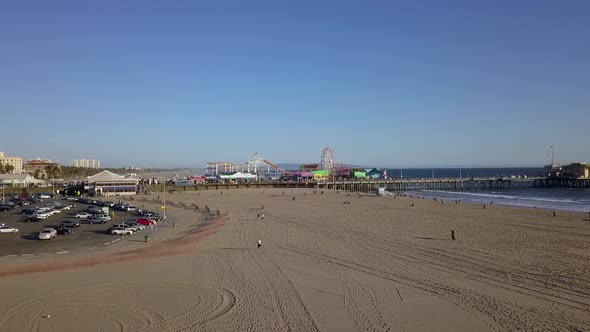 People on beach, parking lot in front of Santa Monica Pier.Amazing aerial view flight fly forwards