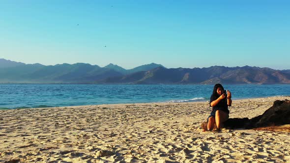 Young happy lady travelling having fun on the beach on clean white sand and blue 4K background