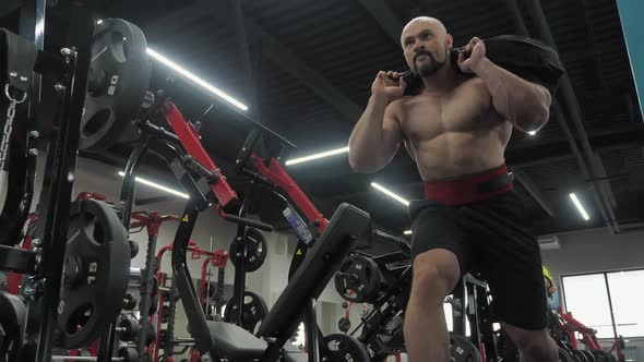 Strong Man Doing Squat Lunges Exercise with Cargo on Weight Training in Gym