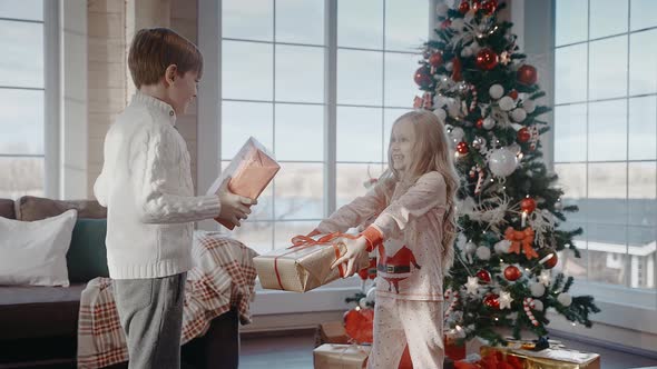 Boy and Girl are Happily Jumping with Gifts and Hugging on Christmas Morning