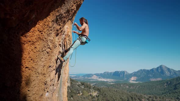 Young Fit Muscular Attractive Man Rock Climbing Outdoors Preparing to Rappel on Rock Face After