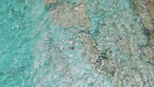 Scuba divers enjoying crystal clear seawater near coastline of Crete island, top down aerial view