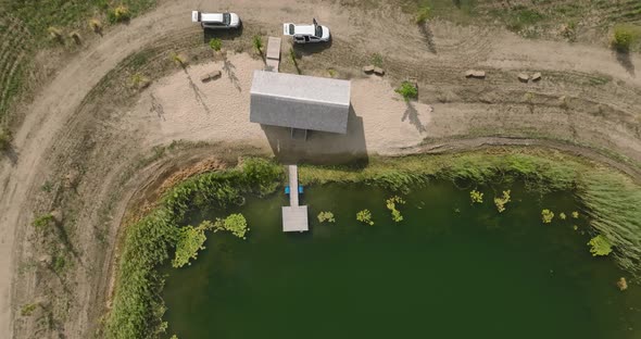 view on a pond over lake and with a gazebo on bank with two cars