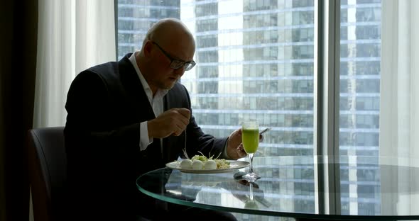 a Businessman in a Business Suit, He Sits in the Office at the Panoramic Window in Which You Can See