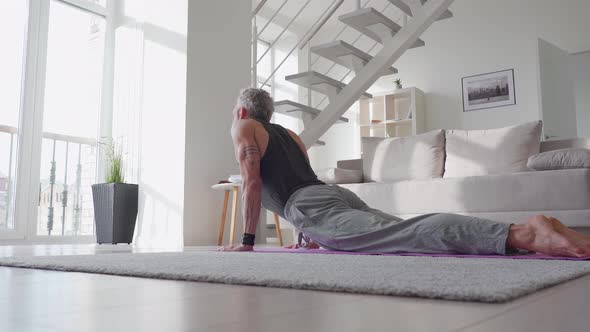 Fit Tattooed Mature Man Doing Morning Workout Yoga Exercise at Home