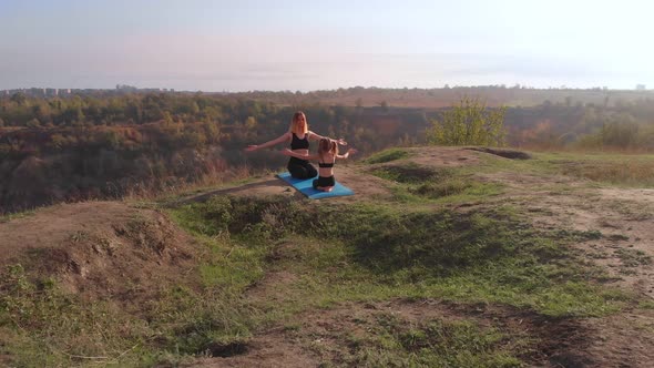 Aerial Top Drone View of Slender Young Mother Do Yoga Exercises with Child Daughter on High Hill in